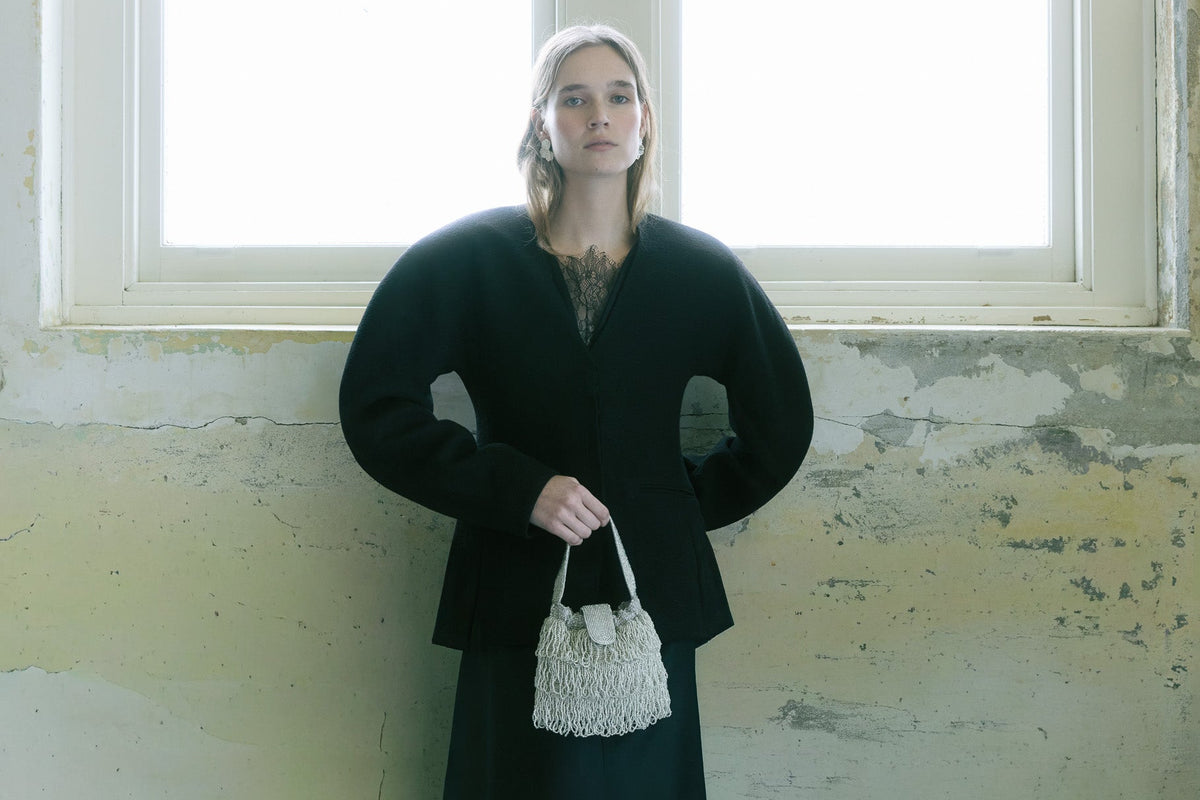 Model standing by window wearing The hold Silver Tassel bag with beaded layered fringes showing evening wear