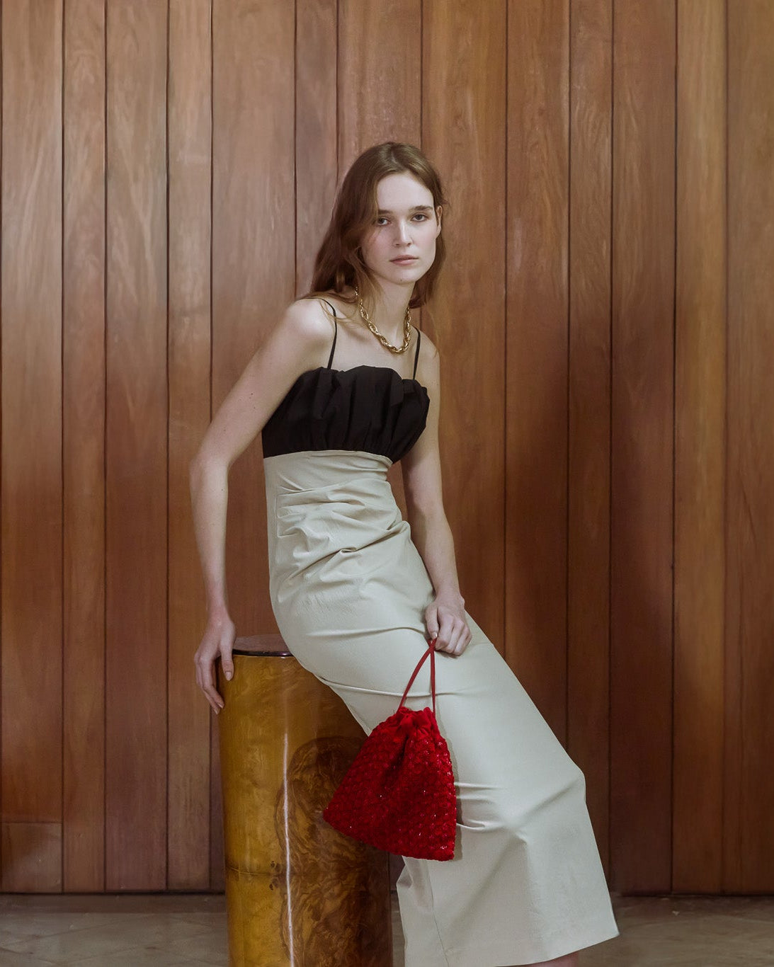 Model carrying a red beaded drawstring bag, styled with a black and ivory evening dress.