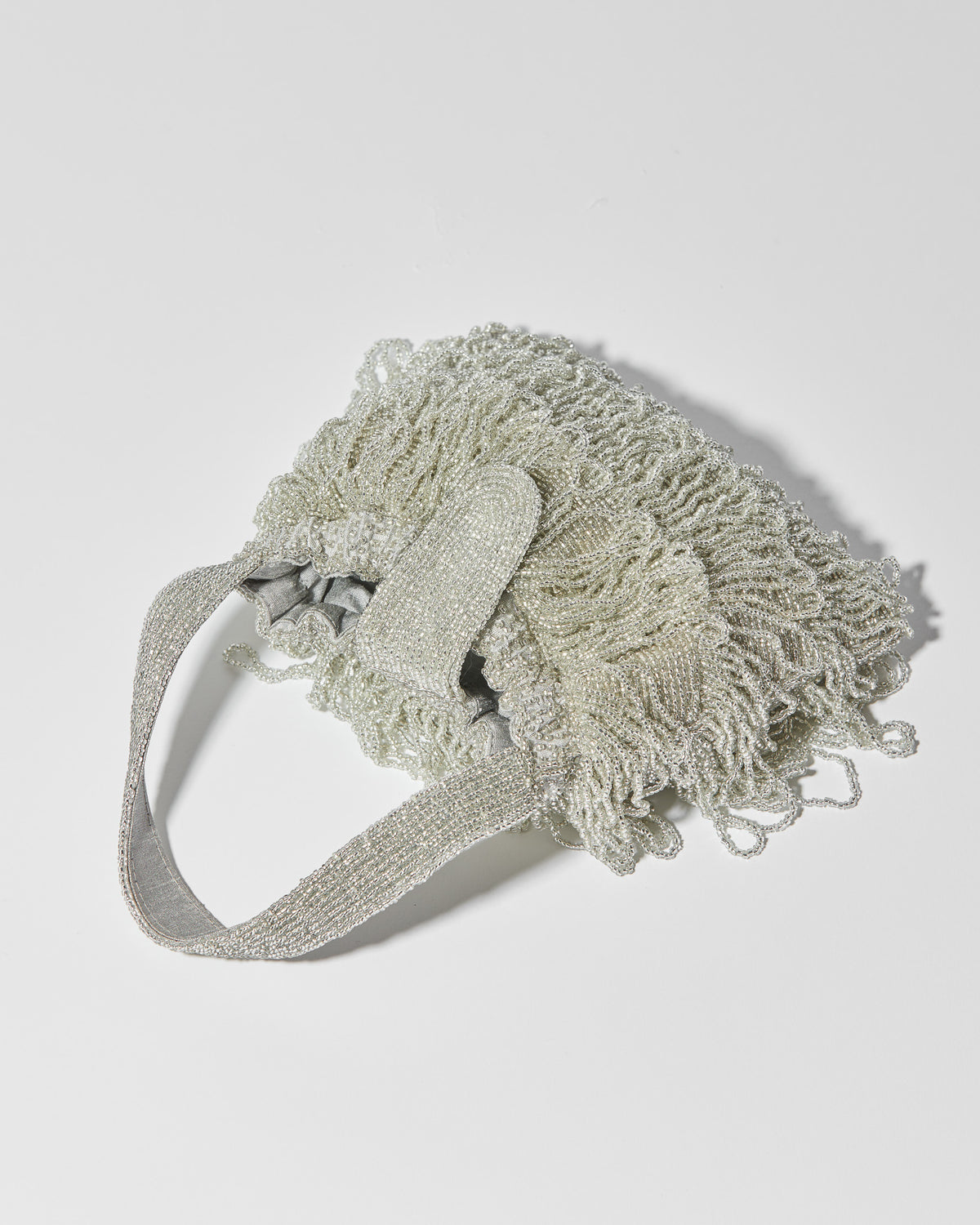 Mira Silver beaded Tassel bag with layered fringe, top strap laying down by the hold