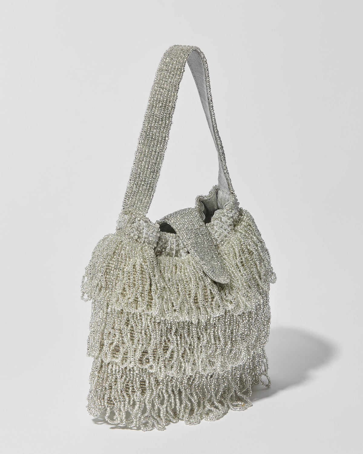 side view of Mira Silver beaded Tassel bag with layered fringe, top strap by the hold