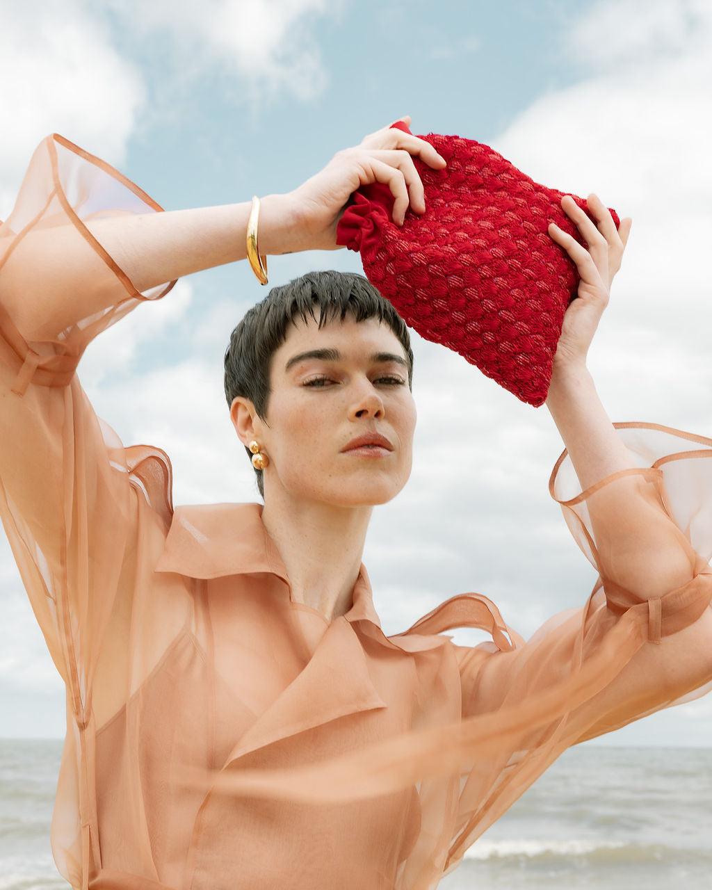 Close-up of a model holding the As Always pouch, highlighting the intricate hand-woven glass beads and vibrant red color.