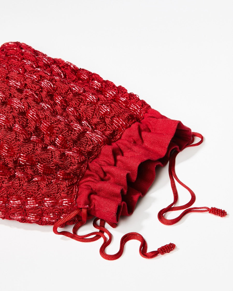 Macro detail of the hand-dyed red glass beads and crochet body, illustrating the shimmering, refined craftsmanship.