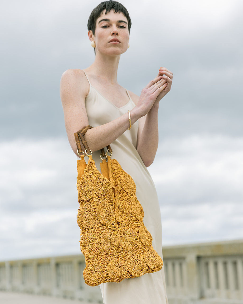 Model carrying the ochre Enveloped Tote over her shoulder, demonstrating how the versatile design transitions from arm to shoulder wear.