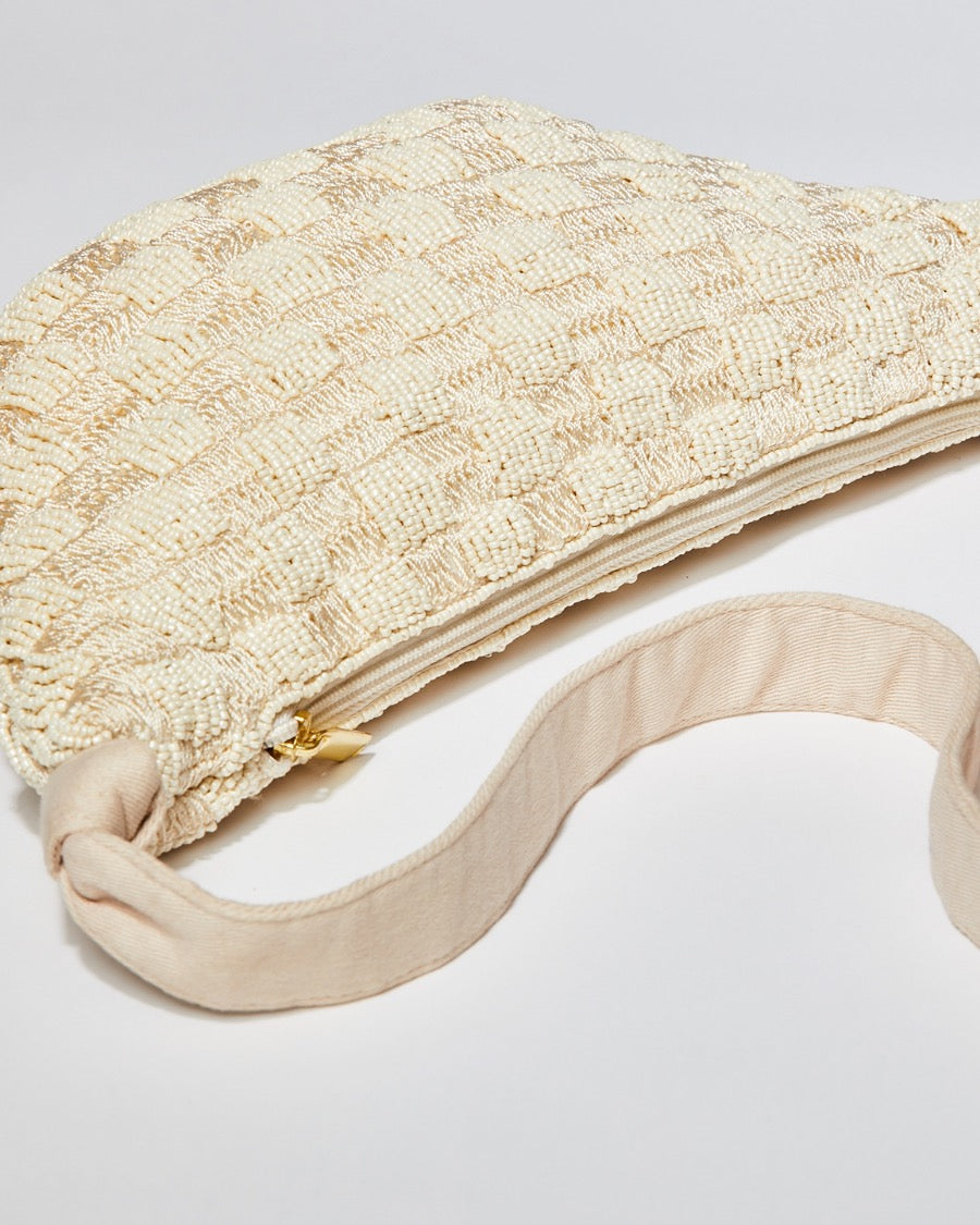 High-angle view of the cream Moving Through bag highlighting the natural cotton strap and the intricate pattern of hand-dyed glass beads.