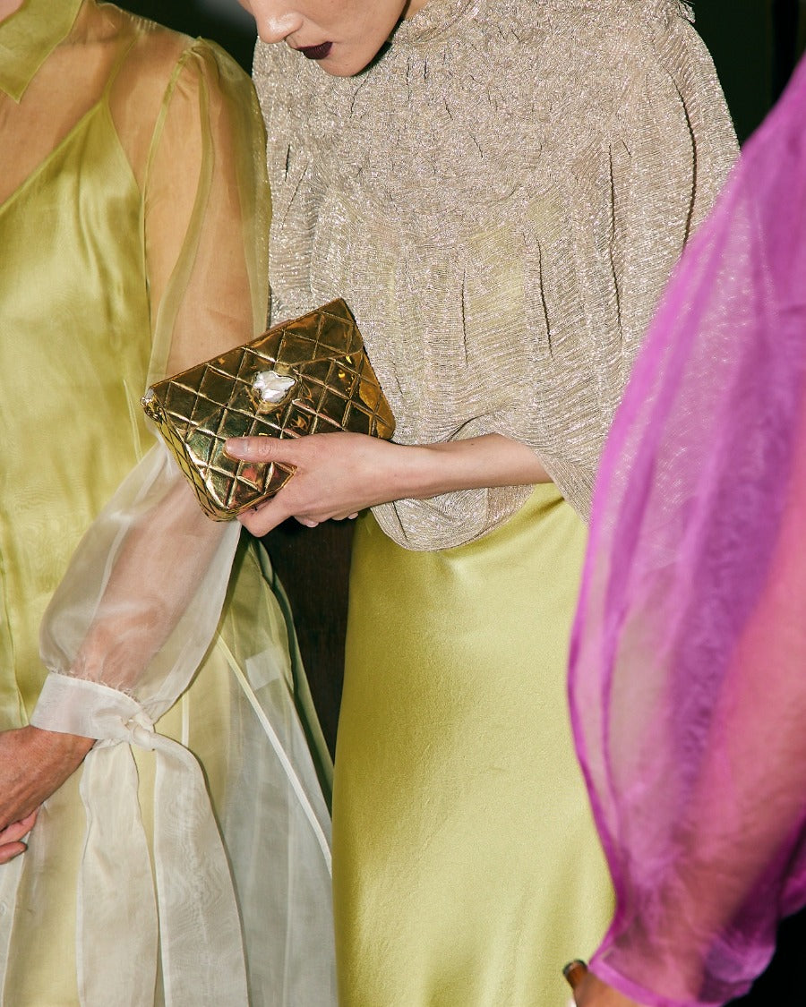 Candid lifestyle view of the gold metal bag paired with an elegant silk dress, perfect for weddings and special celebrations