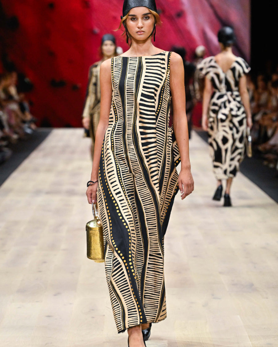 Model styling the Perception of Time gold bag on a fashion runway, showcasing its striking presence as a piece of wearable art.