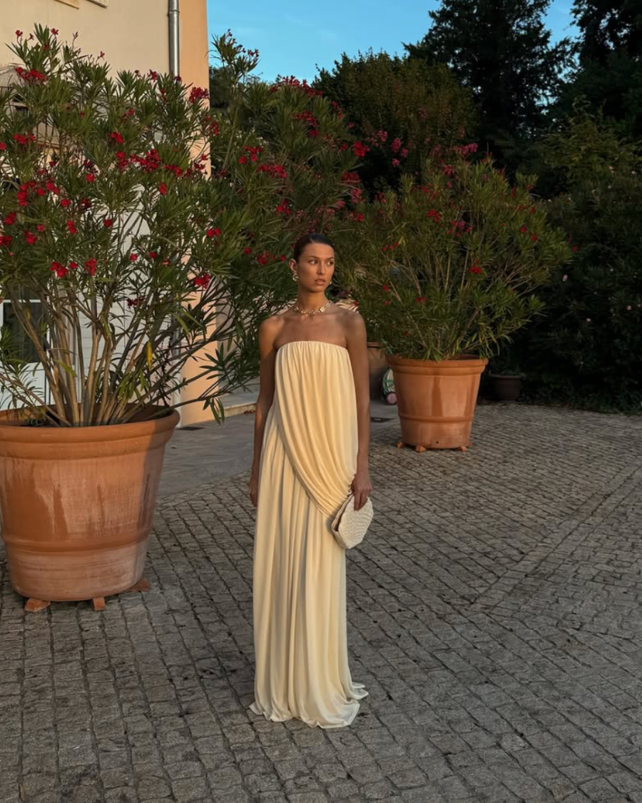Model in a pale yellow formal gown holding the Stand Still beaded shell clutch, an elegant statement piece for weddings and events.