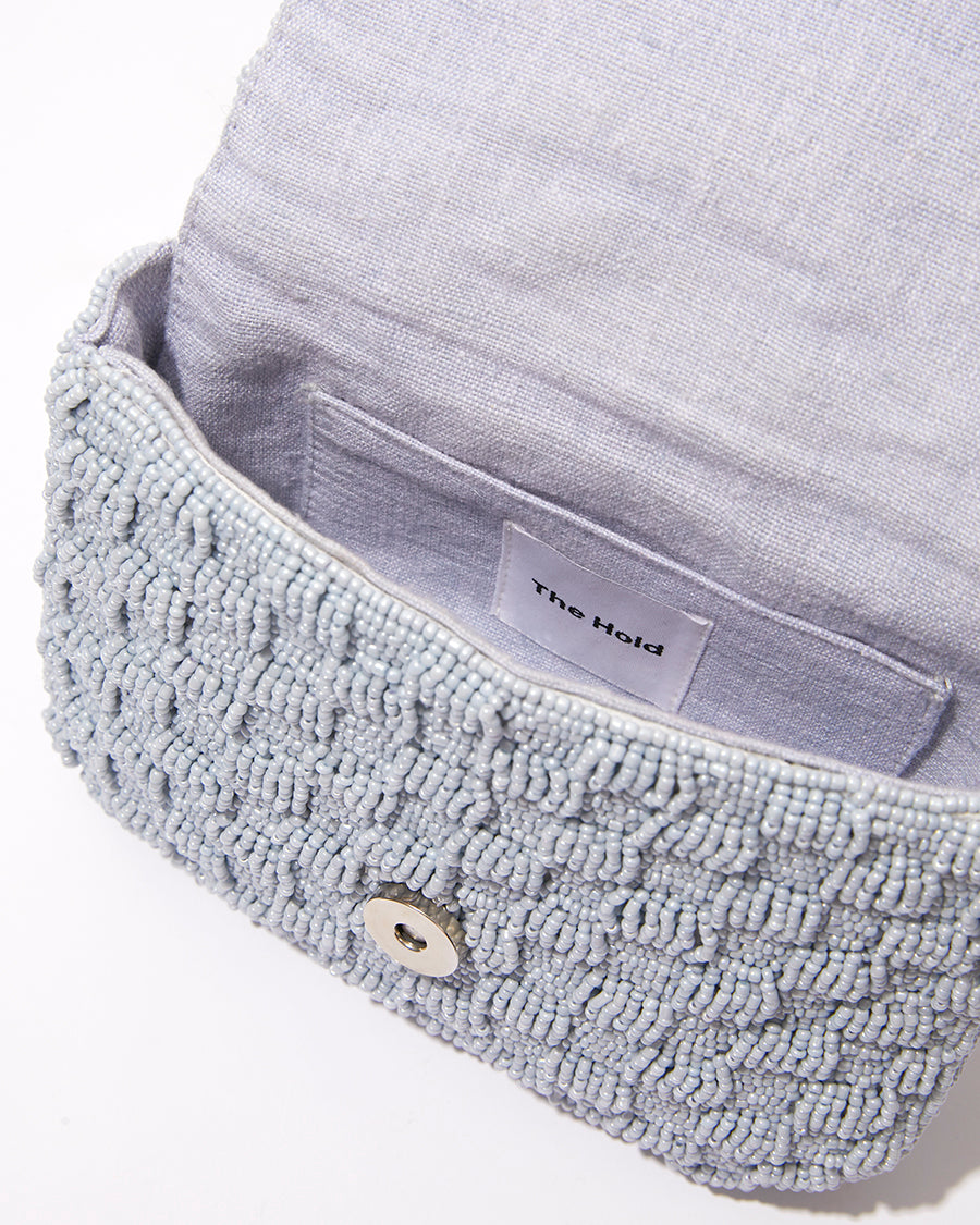 Open view of the Uncovered Layers waist bag showing the natural jute lining and internal magnetic closure for secure storage.
