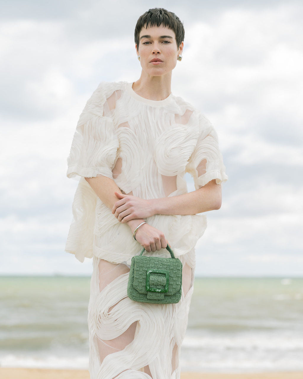 Model walking outdoors carrying the jade green Uncovered Layers bag, demonstrating its use as an elevated everyday accessory.