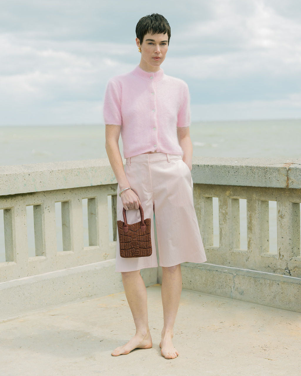 Model styling the artisan-made burgundy beaded bag with a casual outdoor outfit, showcasing a minimalist fashion trend.