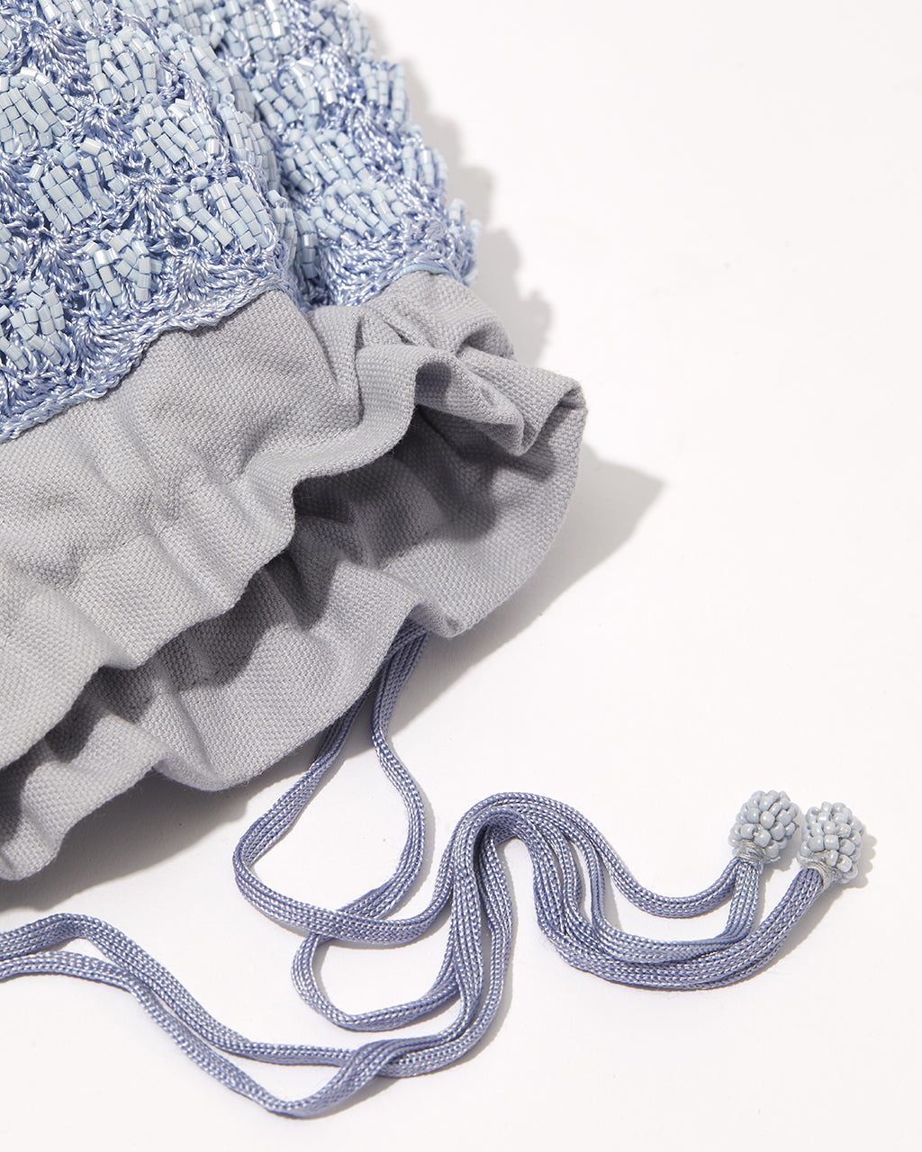 Close-up of His Eyes blue beaded bag showing beadwork texture and drawstring detaill.