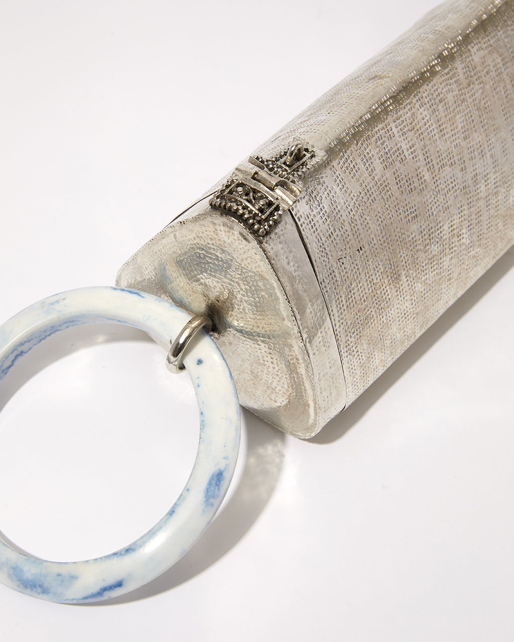 Close-up detail of the round blue marble resin handle and the intricate brass clasp on the triangular Right Off The Edge bag