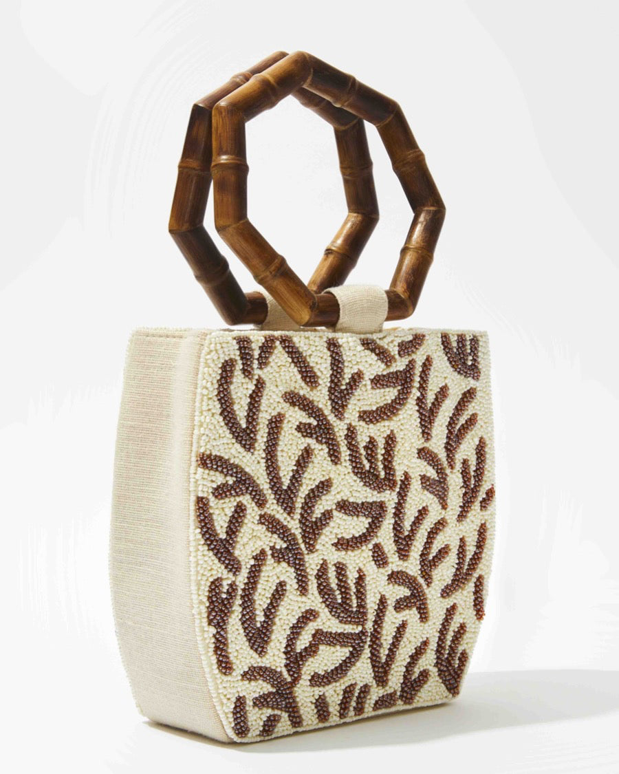 Full front studio shot of the Symbolic Path bag, emphasising the contrast between the natural bamboo top handles and the ivory beadwork.