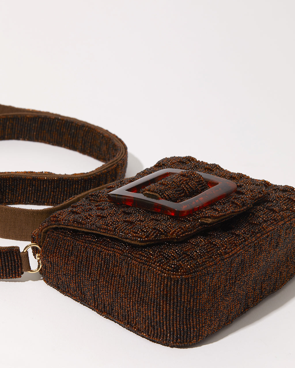 Side view of the brown woven beaded bag showing the matching detachable strap for trendy crossbody or shoulder wear.