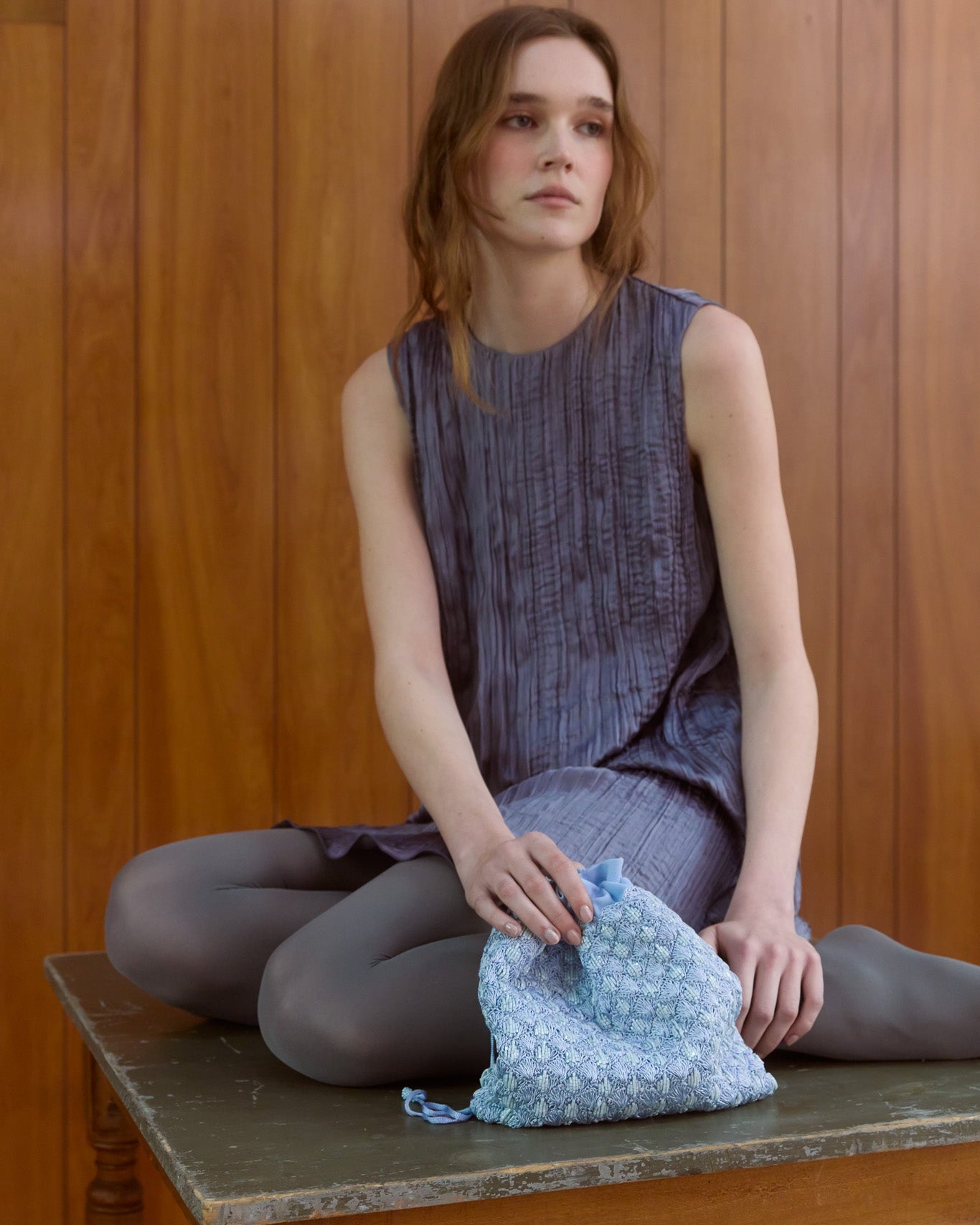 Girl wearing purple dress holding blue beaded pouch bag by the hold