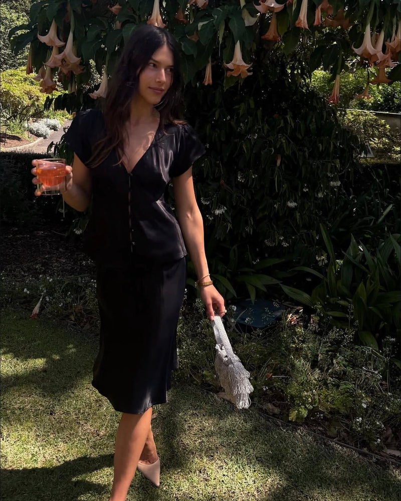 Girl at outdoor event wearing black dress holding Silver beaded tassel fringed bag by the hold 