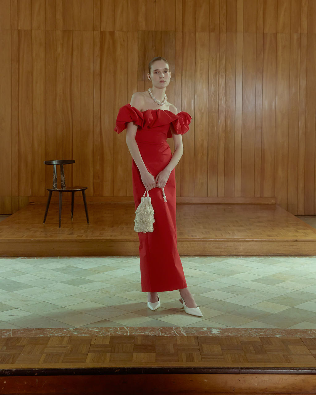 Model in red dress holding ivory beaded tassel bag by drawstrings showing use for as a evening bag 