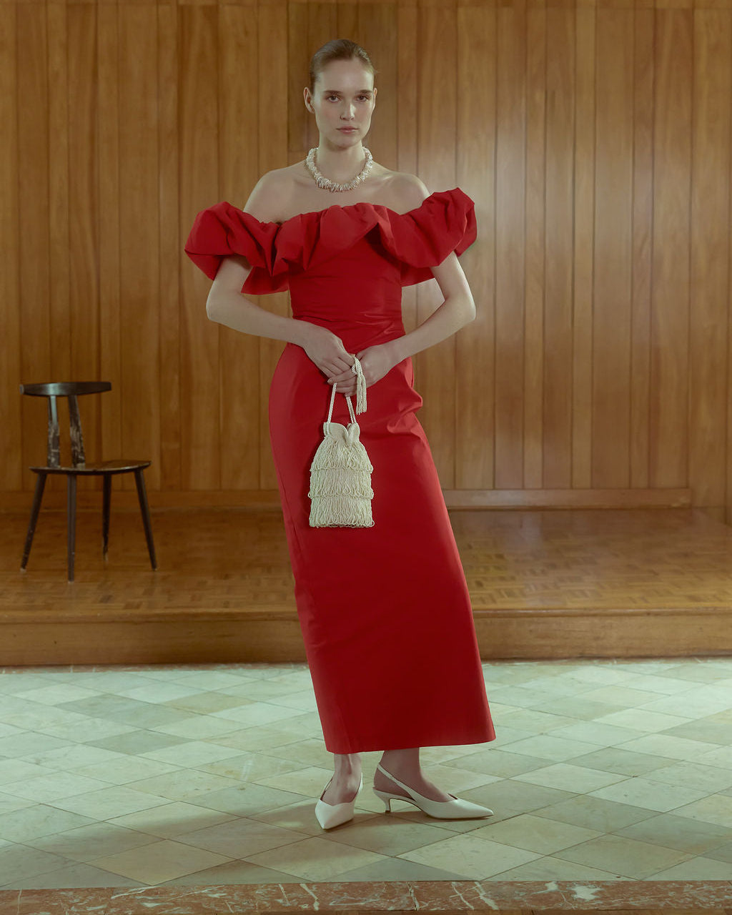 Model in red dress, holding ivory evening pouch with fringe tassels 