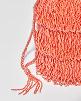 side detail  and close up of beaded drawstring tassels of coral beaded bag featuring three layers of beaded tassel fringe.
