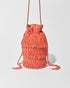 A coral beaded crossbody bag featuring three layers of beaded tassel fringe, a gathered drawstring top and long braided strap with beaded tassel ends.
