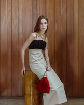 Model carrying a red beaded drawstring bag, styled with a black and ivory evening dress.