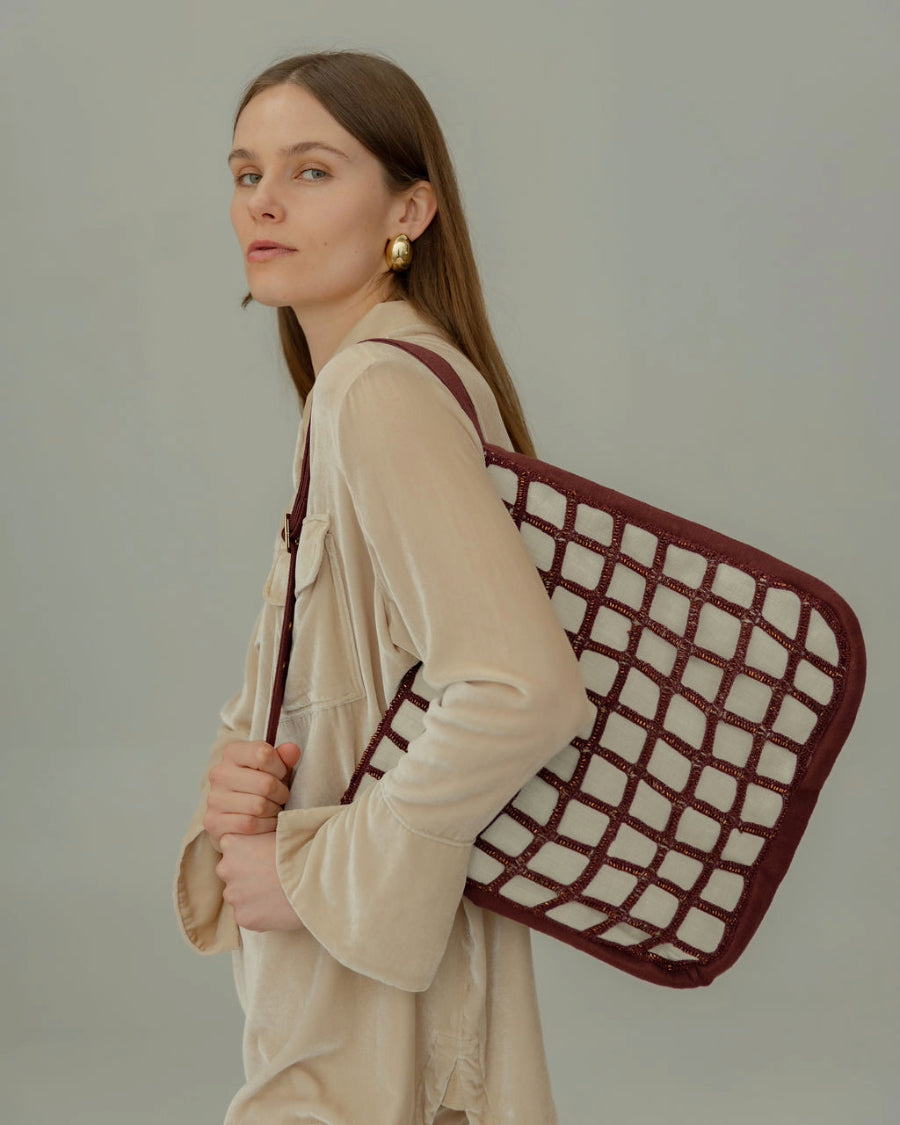 A model carries the Returning Form tote bag, showing its sculptural, slow-fashion silhouette as wearable art by The Hold label.