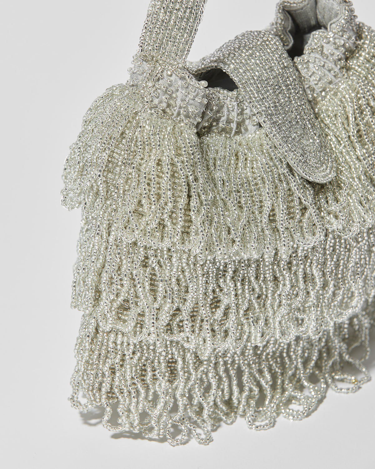 Silver beaded Tassel bag with layered fringe and beaded flap closure close up view.
