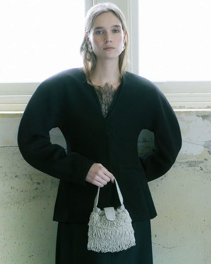 Model in black dress holding silver beaded tassel bag with fringes by top handle