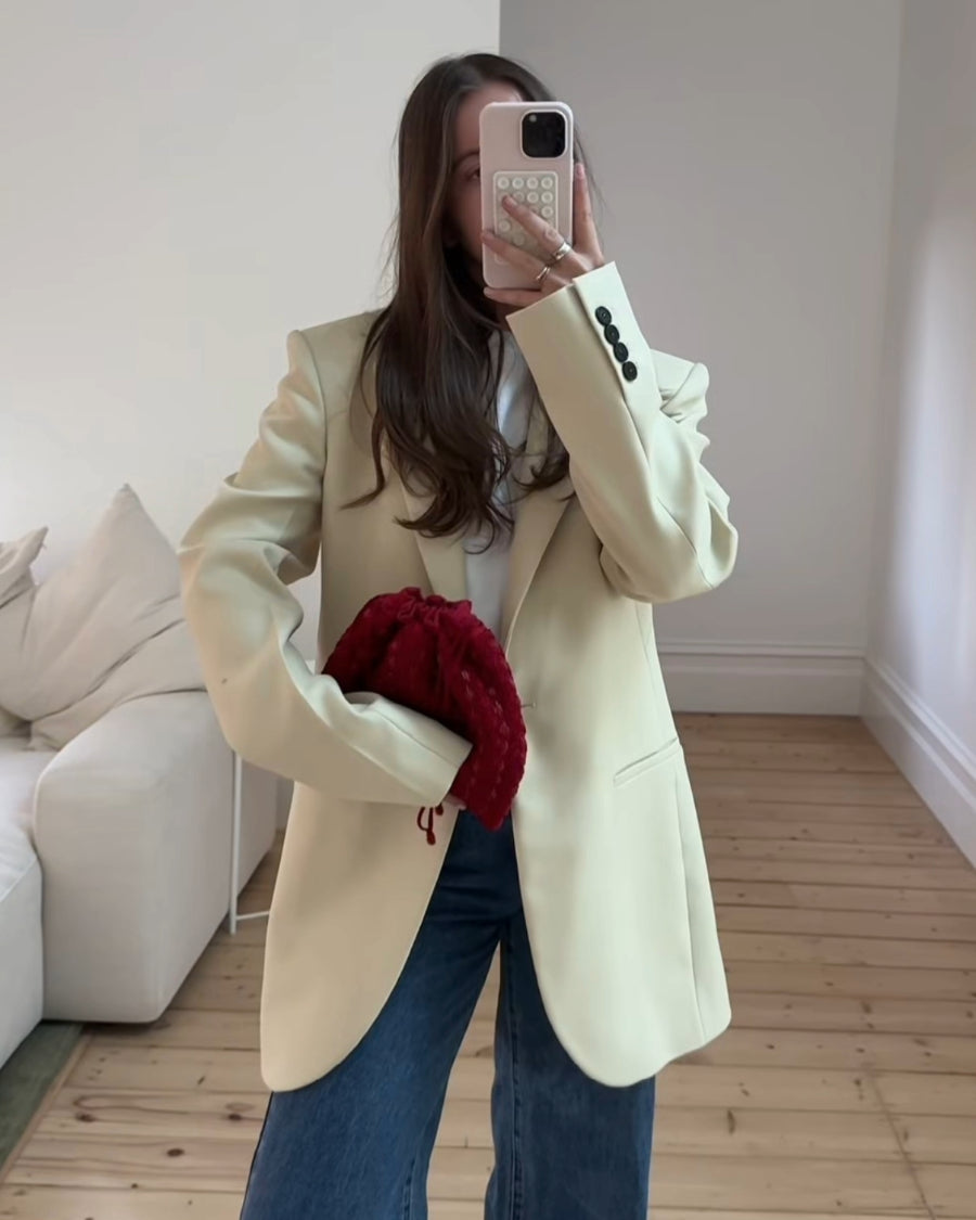 Mirror selfie of a model styling the red beaded pouch with an oversized blazer, showing its capacity to fit an iPhone Plus and essentials.