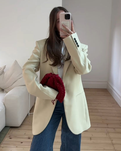 Mirror selfie of a model styling the red beaded pouch with an oversized blazer, showing its capacity to fit an iPhone Plus and essentials.