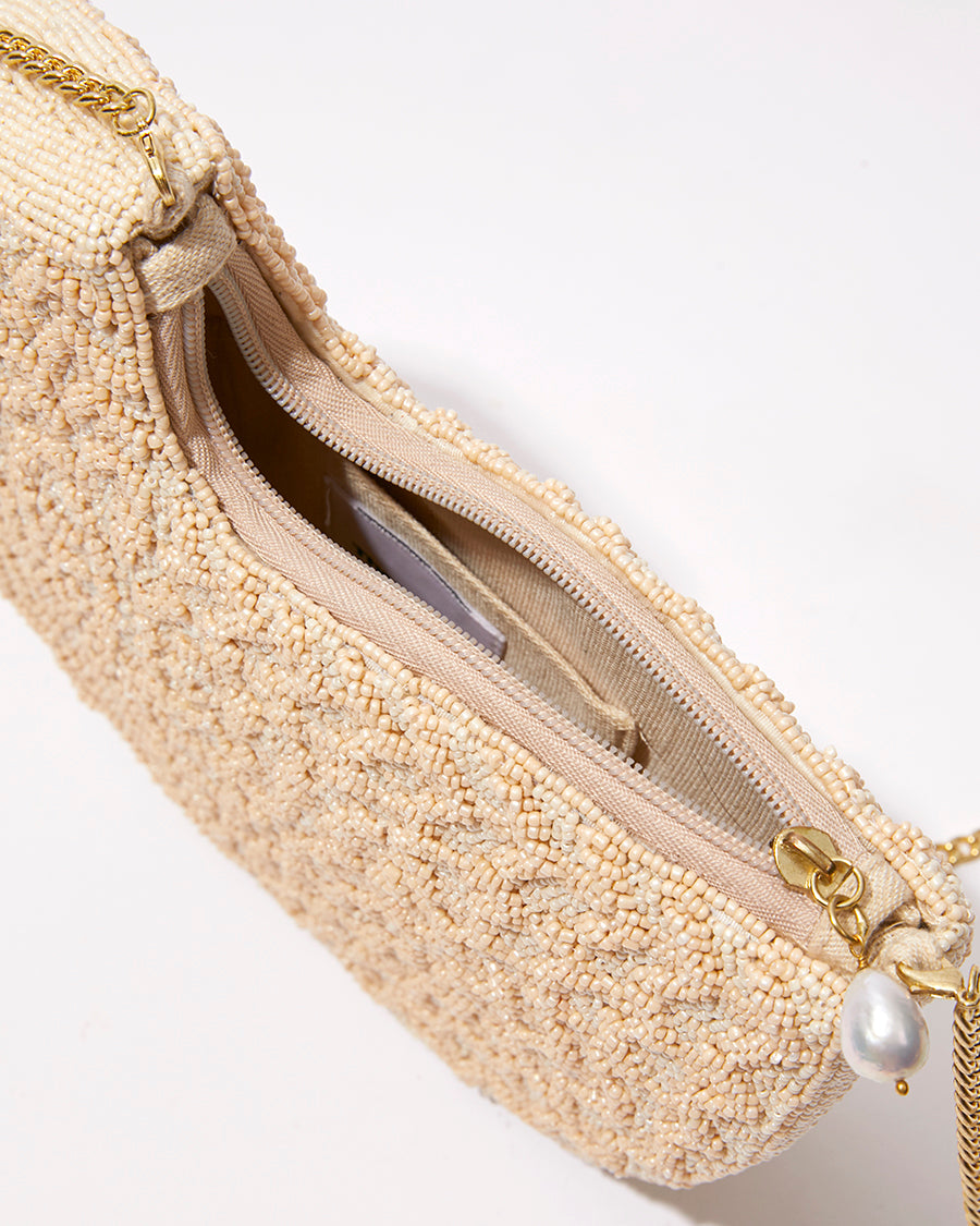 Top-down view of the open Beyond Us clutch showing the natural jute lining and the signature baroque pearl detail at the gold zipper.