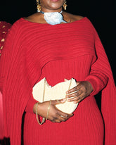 Model in a red pleated gown holding the Beyond Us clutch, demonstrating its presence as a striking statement piece for cocktail evenings and galas