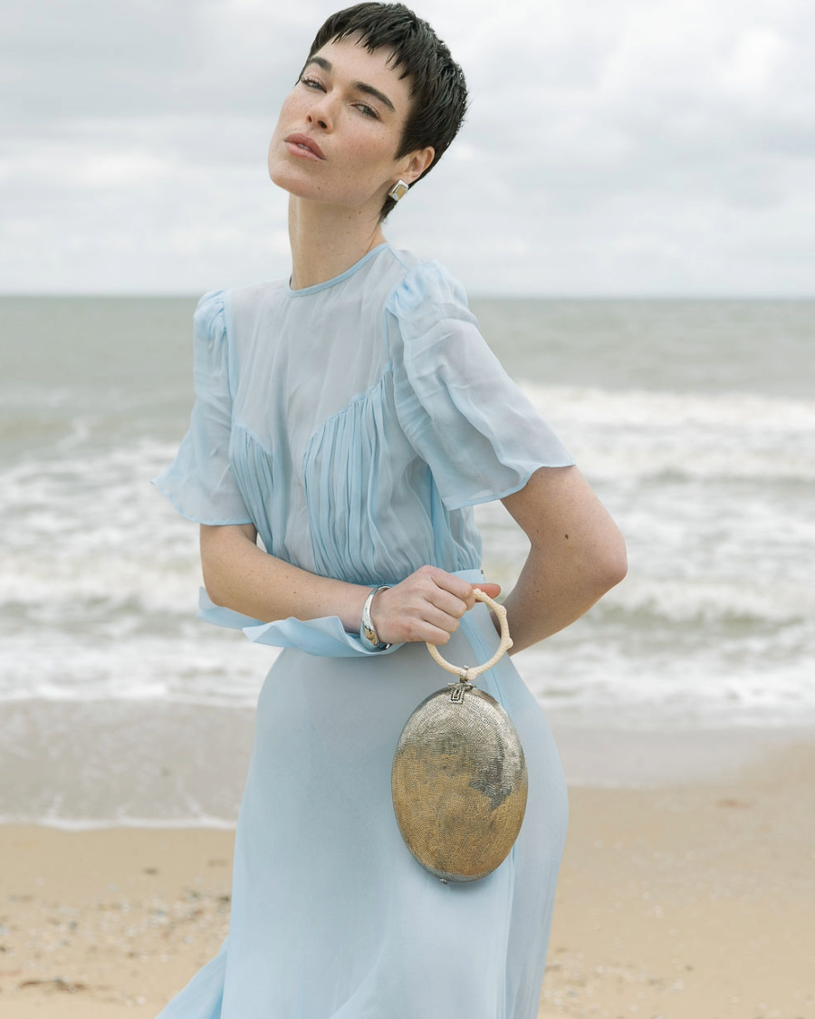 Close up view of a model carrying the silver Capacity for Presence bag, demonstrating its elegant scale and artistic presence for special celebrations.
