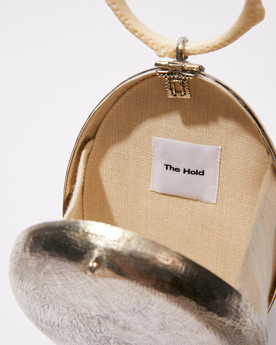 Internal view of the open metal bag showing the natural jute lining and enough space to fit an iPhone Plus and evening essentials.