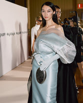 Model styling the Capacity for Presence bag on a red carpet with a light blue gown, showcasing it as a statement event handbag.