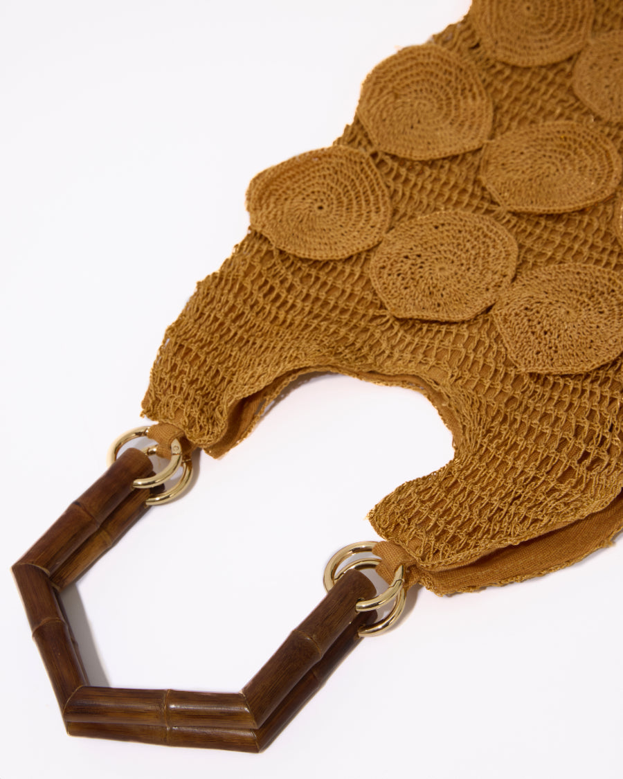Close-up detail of the dark wooden bamboo handles and the intricate hand-crochet body of the Enveloped Tote bag.