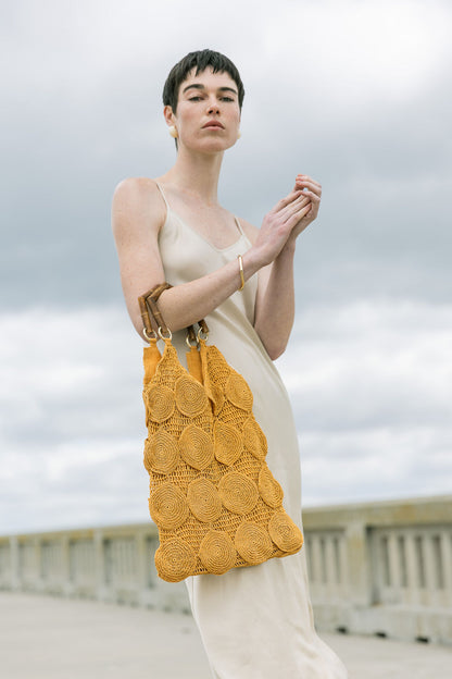 Model carrying the ochre Enveloped Tote over her shoulder, demonstrating how the versatile design transitions from arm to shoulder wear.