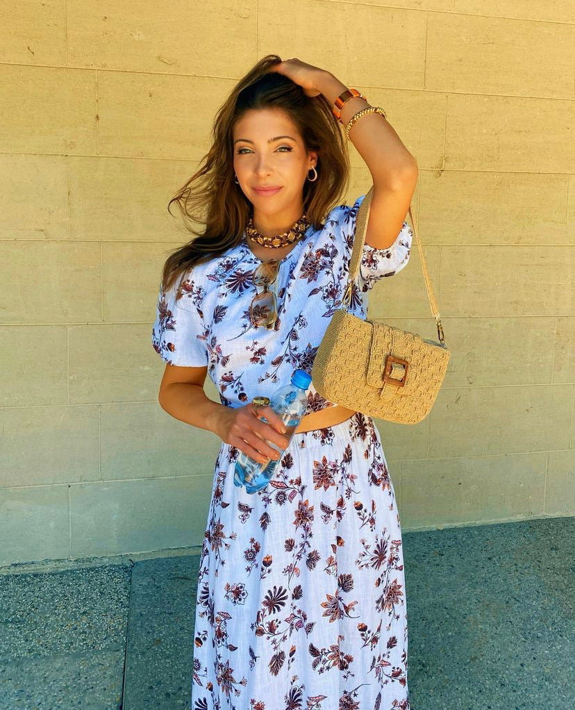 UCG in a blue floral dress holding the Familiar Way bag as a clutch, demonstrating its elegance for lunches and daytime events.