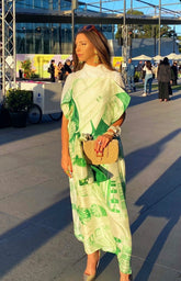 UCG in a green maxi dress styling the tan Familiar Way bag as a shoulder bag for a sophisticated cocktail or wedding guest look.