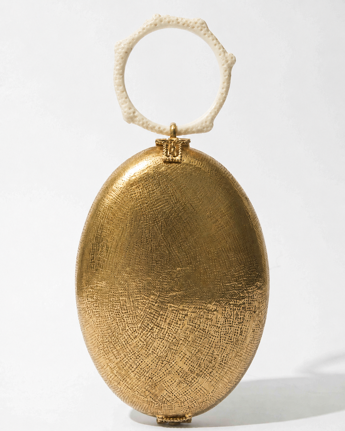 Front studio view of the Capacity for Presence Gold metal bag, featuring an oval hand-beaten brass body and a cream coral-inspired resin handle.