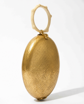 Side profile of the Capacity for Presence bag emphasising the contrast between the gold metal body and the sculptural hand-poured coral handle.