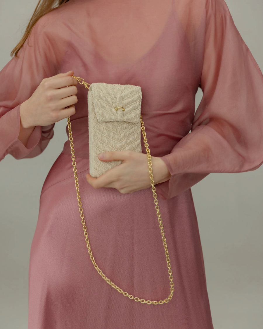 Model in a sheer pink dress wearing the Graceful Cascades mini bag as a crossbody, showcasing its elegant 17cm height and artisanal texture