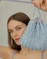 Model holding His Eyes blue beaded bag, event and daywear handbag. Close up detail