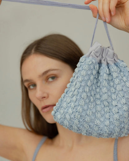 Model holding His Eyes blue beaded bag, event and daywear handbag. Close up detail