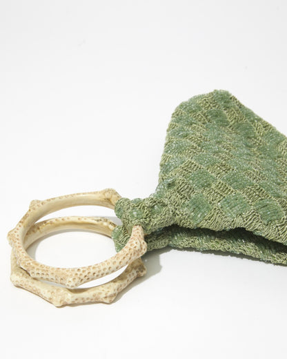 Close-up of Intimate Exchange bag in sage green showing beadwork texture