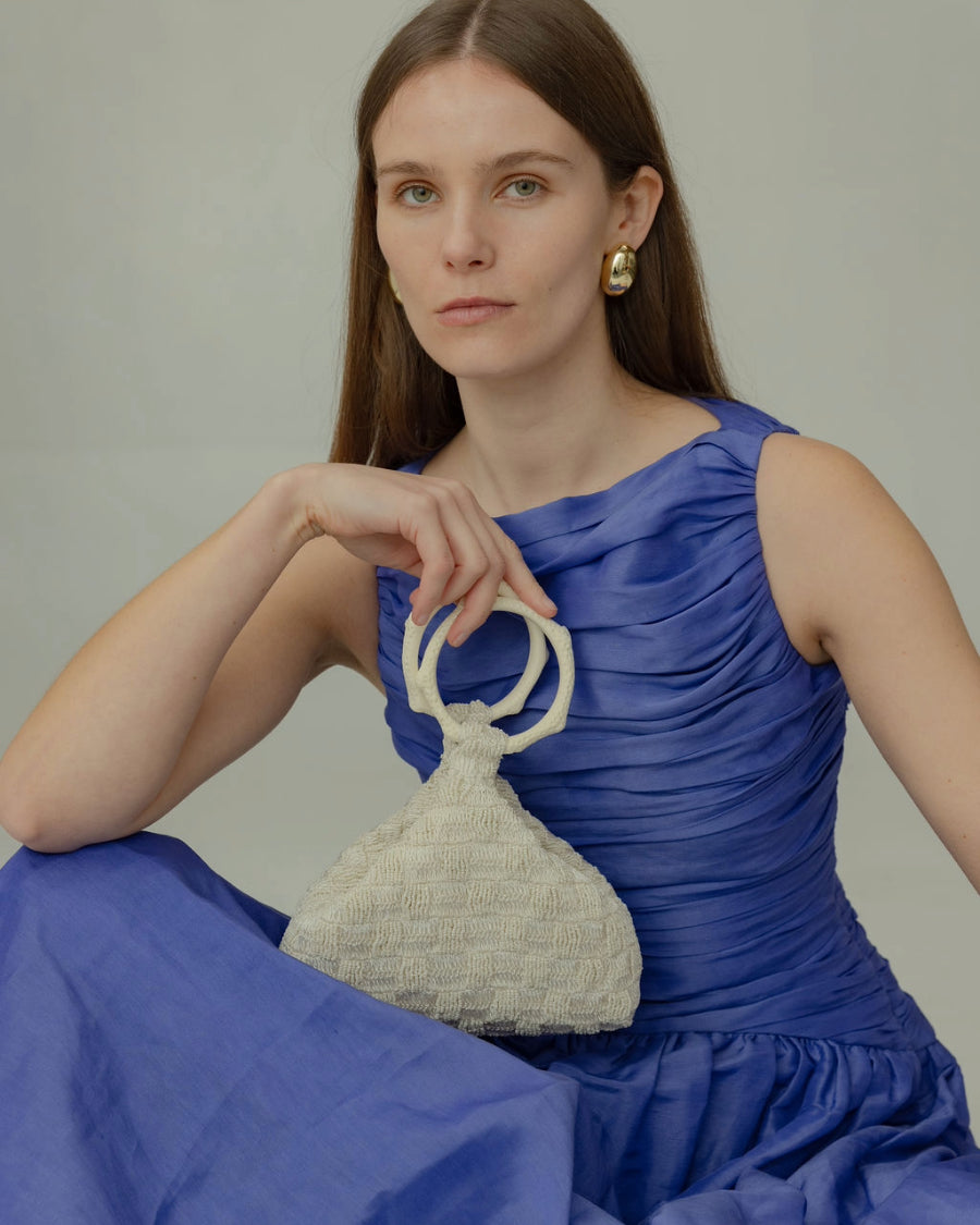 Model holding Intimate Exchange bag in ivory, beaded occasion bag for bridal and wedding bag with pearl detail.