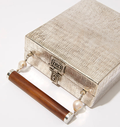 High-angle studio shot of the Modern World bag highlighting the intricate metal clasp and the organic, hand-crafted silver texture.