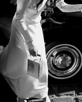 Artistic black and white editorial shot of a model holding the Modern World bag by a vintage car, emphasising its timeless aesthetic.