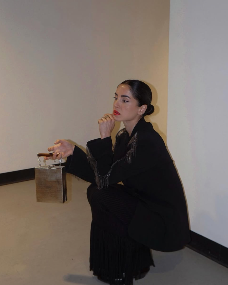 Model in a black suit seated with the Modern World metal bag, showcasing its versatility as a statement accessory for evening occasions.