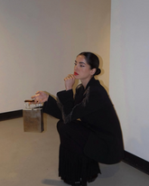 Model in a black suit seated with the Modern World metal bag, showcasing its versatility as a statement accessory for evening occasions.